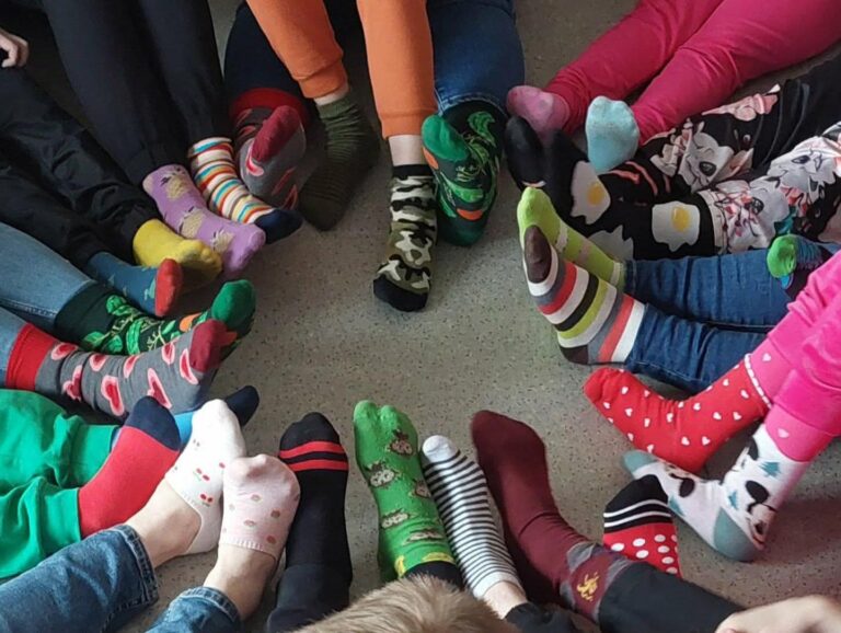 Stopy uczestników w kolorowych, nie do pary skarpetkach podczas obchodów Dnia Kolorowej Skarpetki w OREW w Sadlnie
